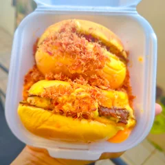 A Corte Pão de brioche, hambúrguer 100g em natura, queijo cheddar fatiado, molho da casa e farofa de bacon. O lanche é cortado ao meio e servido em uma piscina de cheddar cremoso da casa, em embalagem individual.